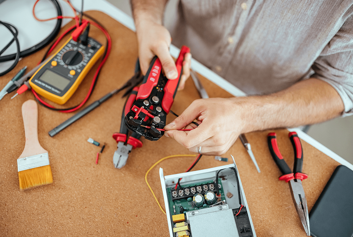 Person repairing electronic device with tools.