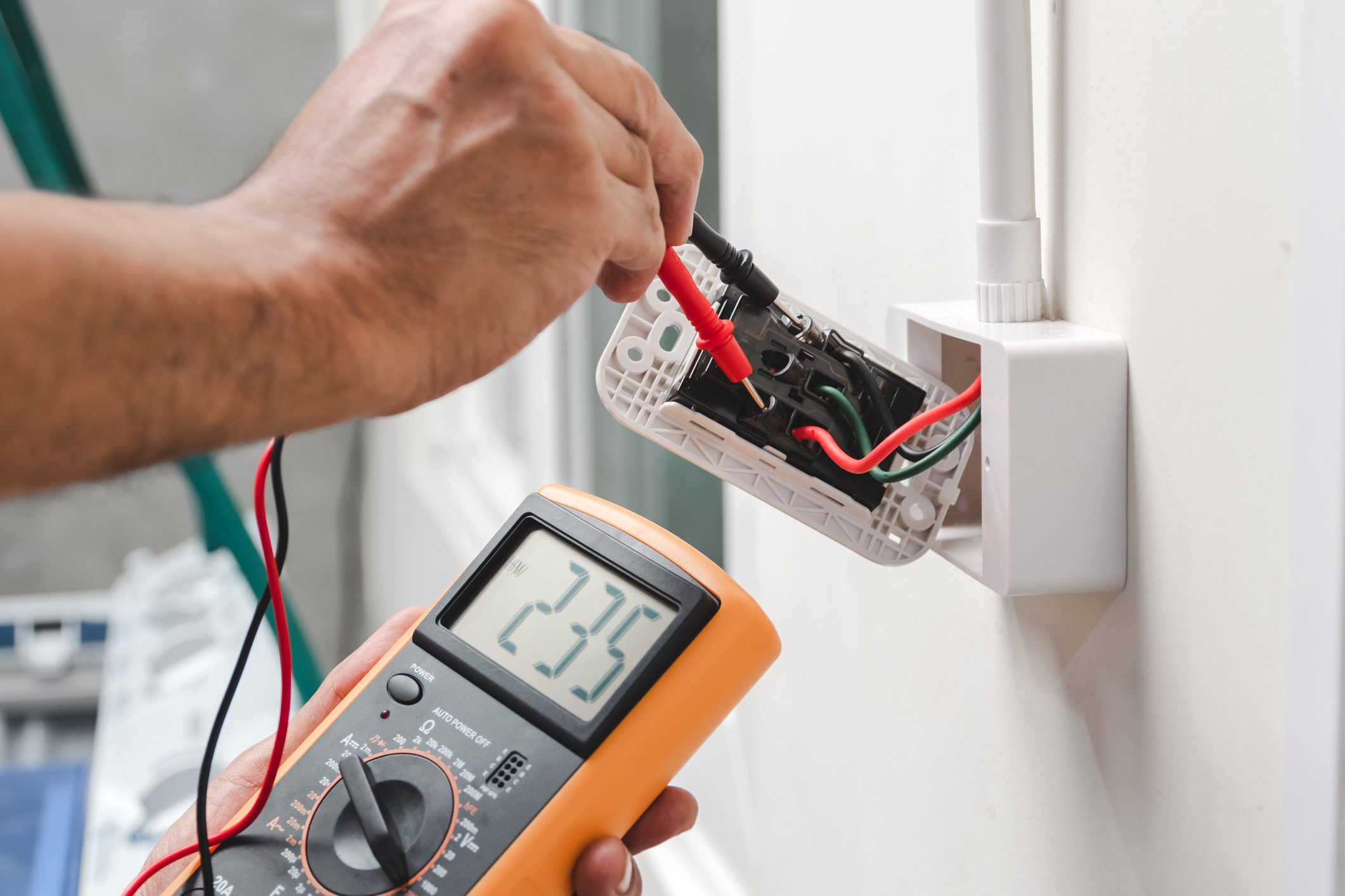 Electrician measuring voltage of wall socket.