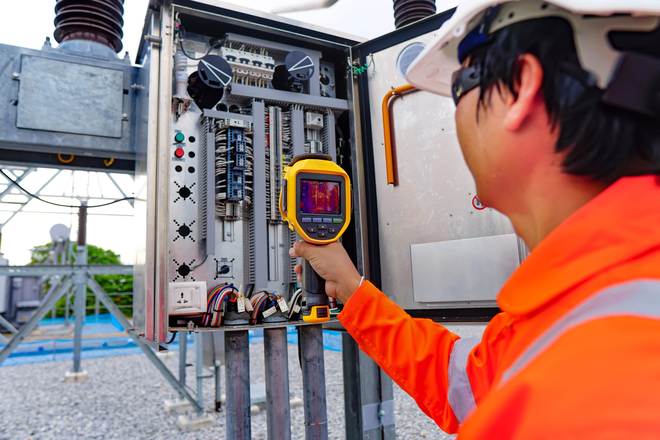 Technician inspecting electrical panel with device.