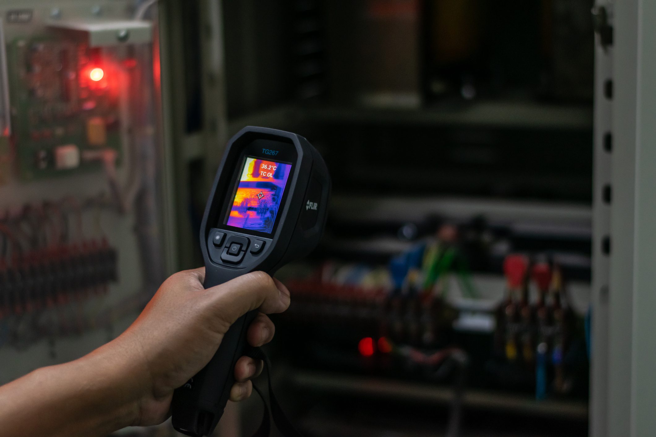 Hand using thermal camera on electrical panel.