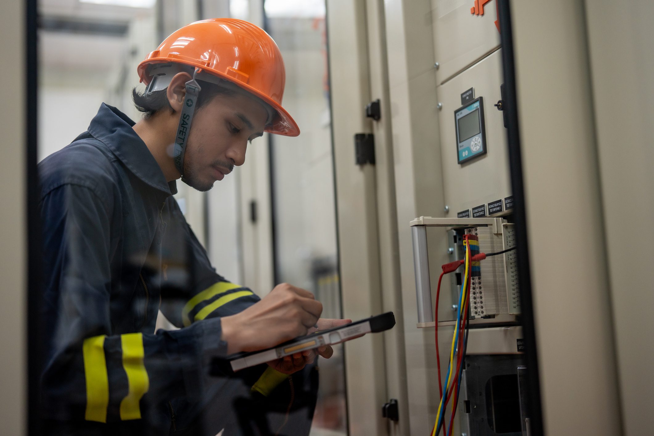 Technician inspecting electrical panel with clipboard.
